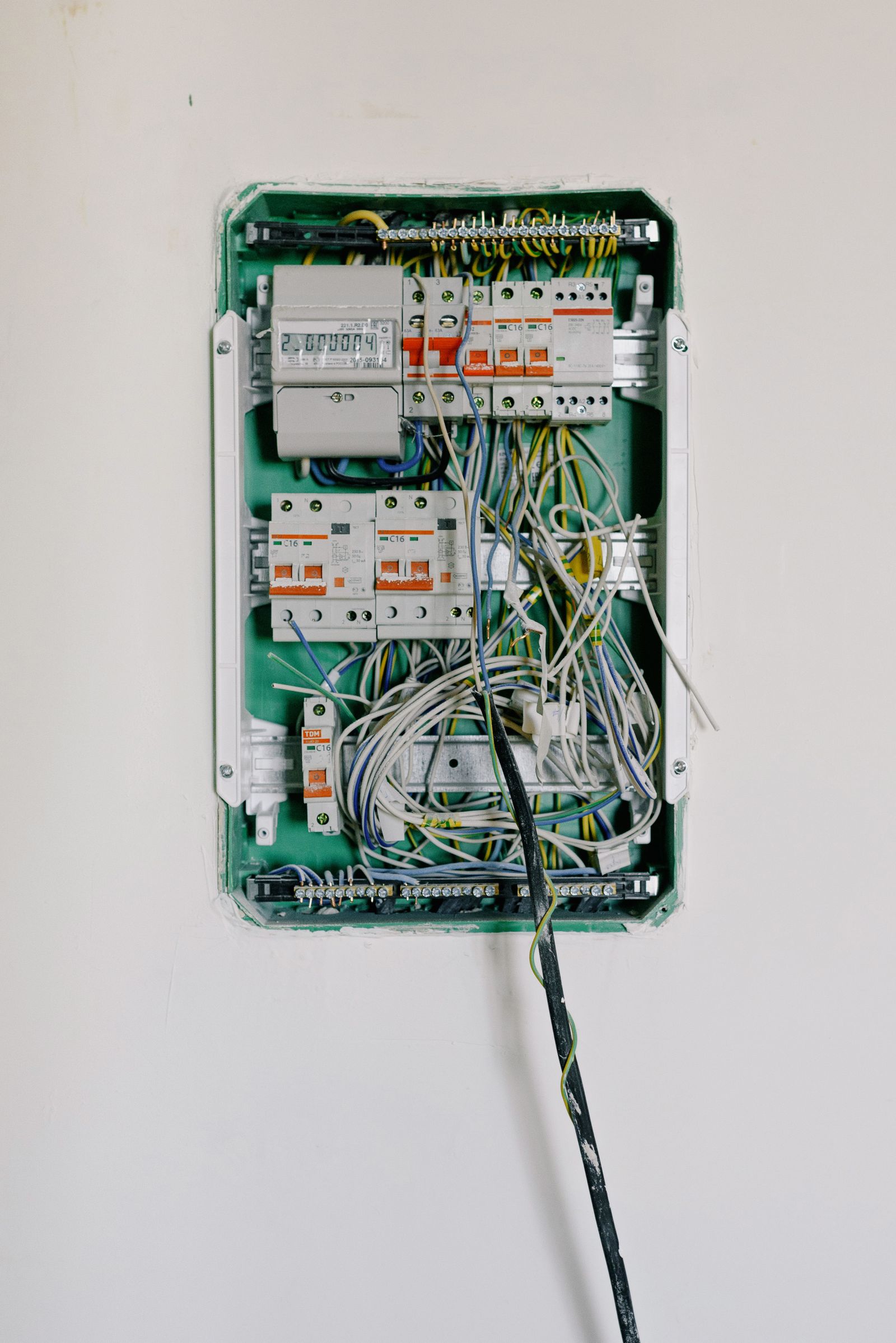 Switchboard with wires connected to electrical switches with circuit breakers installed on white wall